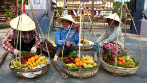 Hoi An, Vietnam - March 20, 2016: Women selling fruits and the street of old town Hoi An, Vietnam